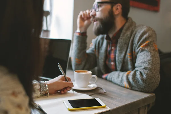 Hipster avec barbe avec smartphone et ordinateur portable sur la table cédant — Photo