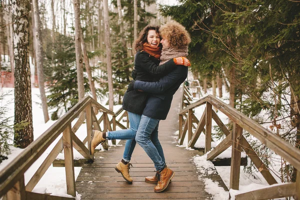 Cabelo encaracolado hipster casal abraçando na floresta de inverno — Fotografia de Stock