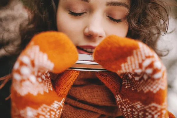 Mooi meisje met ogen gesloten spelen mondharmonica in winter handschoenen — Stockfoto