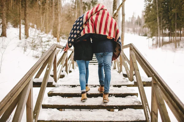 Casal caminhando parque de inverno sob pano de estilo bandeira americana — Fotografia de Stock