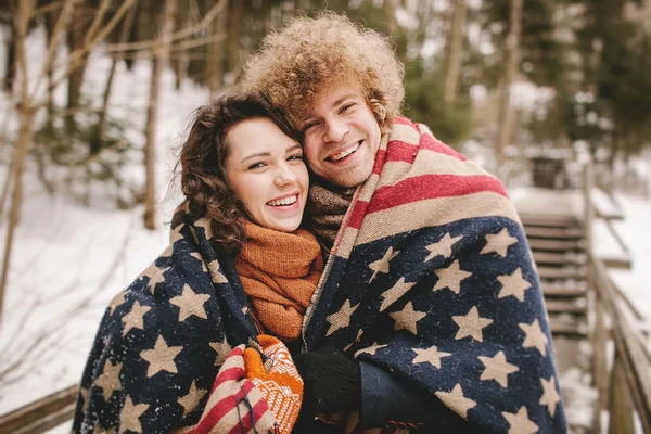 Coppia felice sotto le stelle e strisce tappeto nel parco invernale — Foto Stock