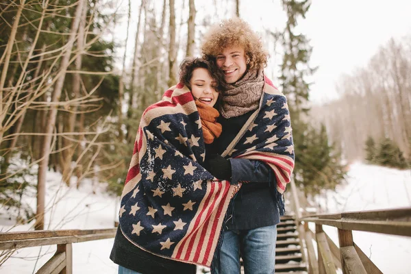 Happy couple under stars and stripes rug in winter park