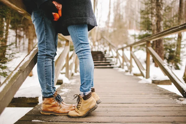 Hipster couple kissing on wooden stairs in winter park — Stock Photo, Image