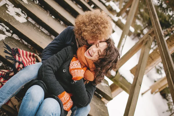 Jovem casal sentado em escadas de madeira ao ar livre no inverno — Fotografia de Stock