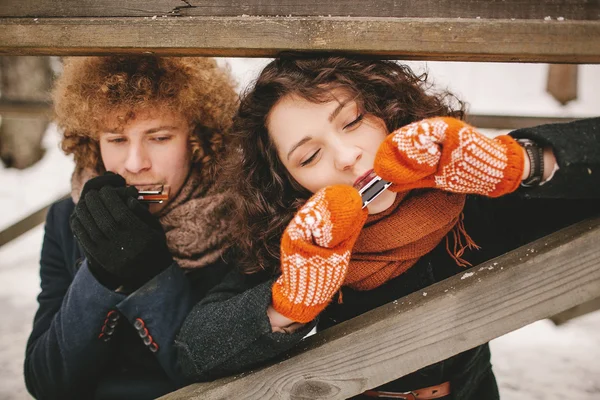 Paar spielt im Winter gemeinsam Mundharmonika im Freien — Stockfoto