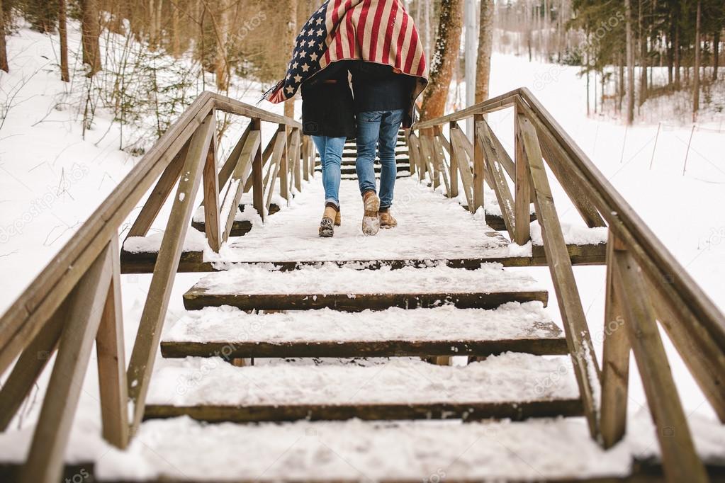 Couple walking winter park under american flag style cloth