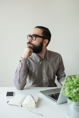 Dizüstü bilgisayar ve smartpho üzerinde düşünme bardaklarda sakallı meşgul adam