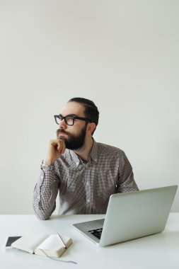 Dizüstü bilgisayar ve smartpho üzerinde düşünme bardaklarda sakallı meşgul adam