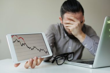 Depressed businessman leaning head below bad stock market chart clipart