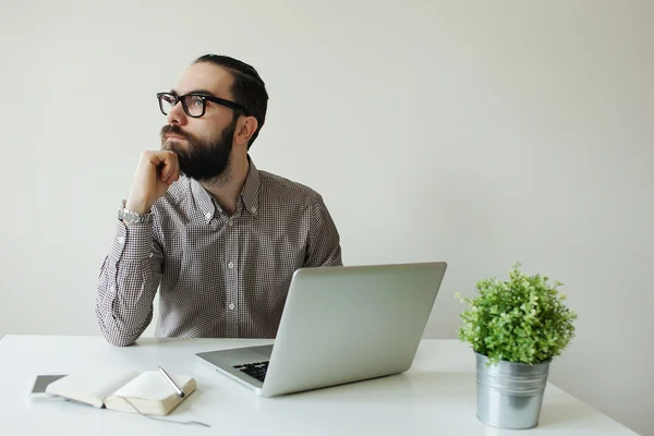 Hombre ocupado con barba en gafas pensando en el portátil y smartpho —  Fotos de Stock