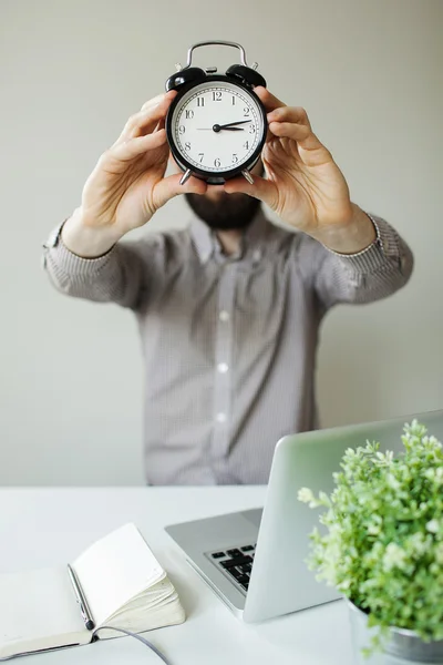 Man with alarm clock head in hands — Stock Photo, Image