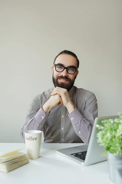 Vriendelijke man met baard in glazen camera kijken over laptop — Stockfoto