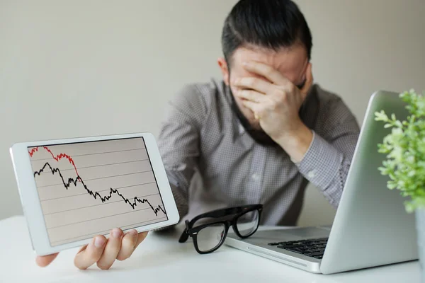 Niedergeschlagener Geschäftsmann lehnt sich kopfüber unter schlechten Börsencharts zurück — Stockfoto