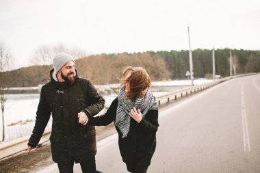 Genç çift el ele tutuşarak boş yolda çalışan