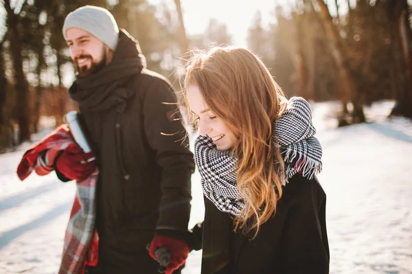 Joven pareja hipster caminando en el bosque de invierno tomados de la mano — Foto de Stock