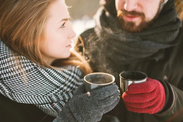 Hipster pareja en el parque de invierno con té caliente de termos — Foto de Stock