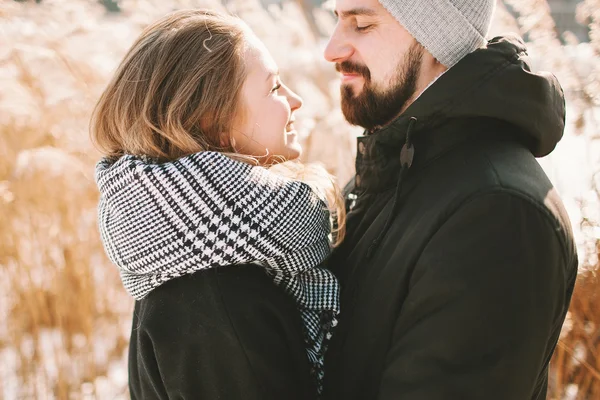 Happy hipster couple hugging near winter lake and reeds — Stock Photo, Image