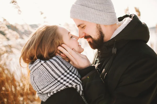 Happy hipster couple hugging near winter lake and reeds — Stock Photo, Image