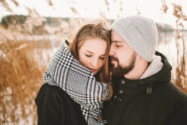 Feliz casal hipster abraçando perto do lago de inverno e juncos — Fotografia de Stock