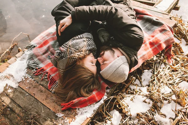 Casal perto deitado em xadrez no parque de inverno — Fotografia de Stock