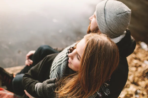 Paar sitzt auf Seebrücke am zugefrorenen See und schaut sich an — Stockfoto
