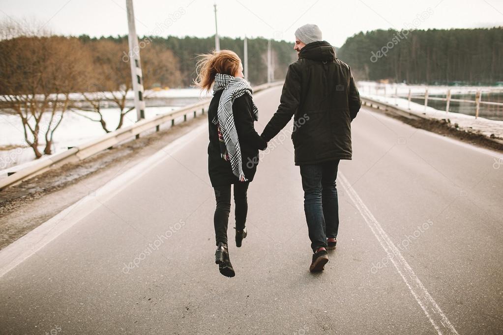 Young couple running on the empty road holding hands — Stock Photo