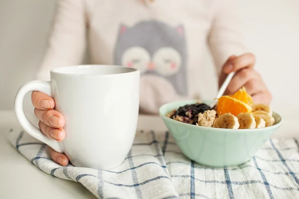 女性は紅茶のカップとスプーン、お粥、フルーツを保持します。 — ストック写真