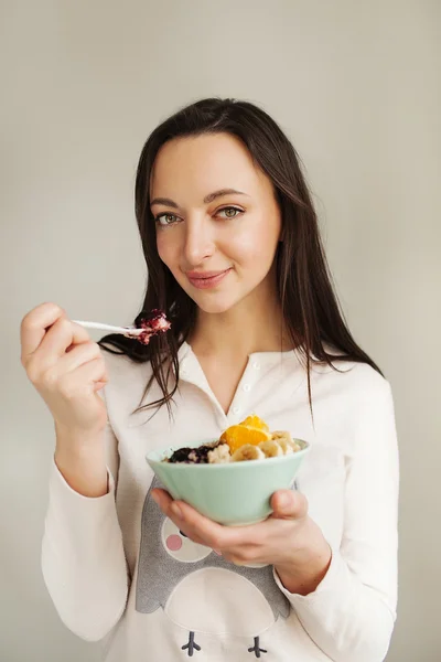 Wanita makan bubur dengan buah-buahan menggunakan sendok — Stok Foto