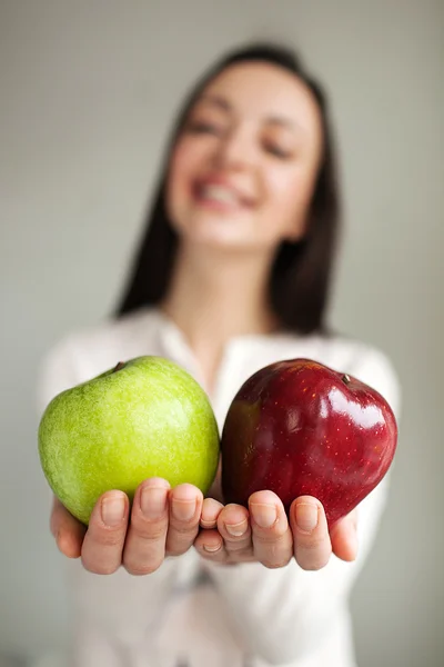 Young woman holds two apples and smiling — Stock Photo, Image