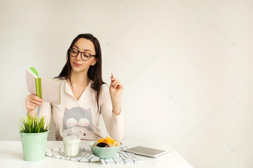 Woman making notes in notepad with healthy food on table