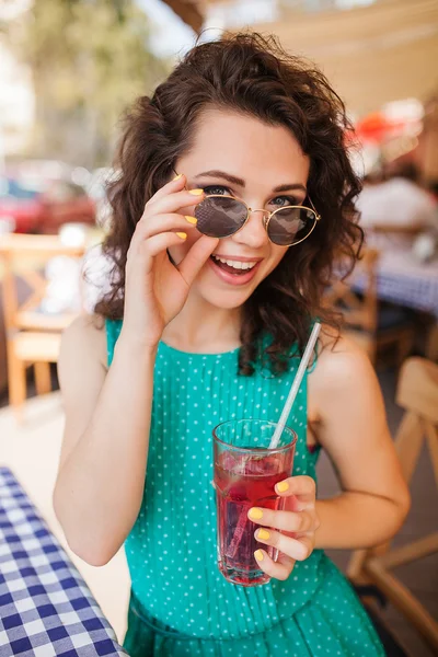 Kvinna i runda solglasögon med cocktail på kafé terrass har roligt — Stockfoto
