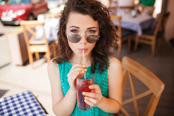 Kvinna i runda solglasögon med cocktail på kafé terrass har roligt — Stockfoto