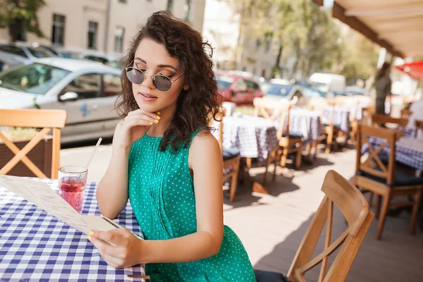 Mulher em óculos de sol redondos com coquetel fazendo ordem no terraço do café — Fotografia de Stock