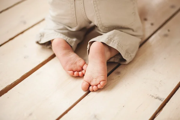 Baby legs in pants on wooden floor Royalty Free Stock Images