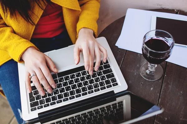 Жінка з червоним винним планшетом і ноутбуком у вуличному кафе — стокове фото