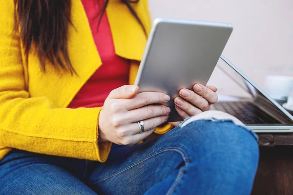 Woman holds tablet sitting outdoors in cafe with laptop — Stock Photo, Image