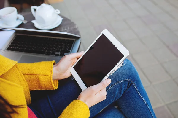 Woman holds tablet sitting outdoors in cafe with laptop — Stock Photo, Image