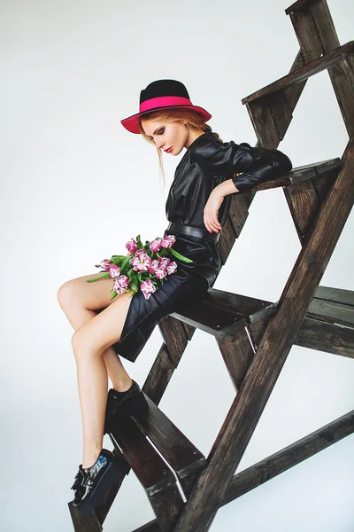 Trendmodel in schwarzem Lederkleid und Hut mit Blumen — Stockfoto