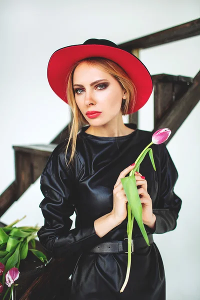 Modelo na moda em couro vestido preto e chapéu com flores — Fotografia de Stock