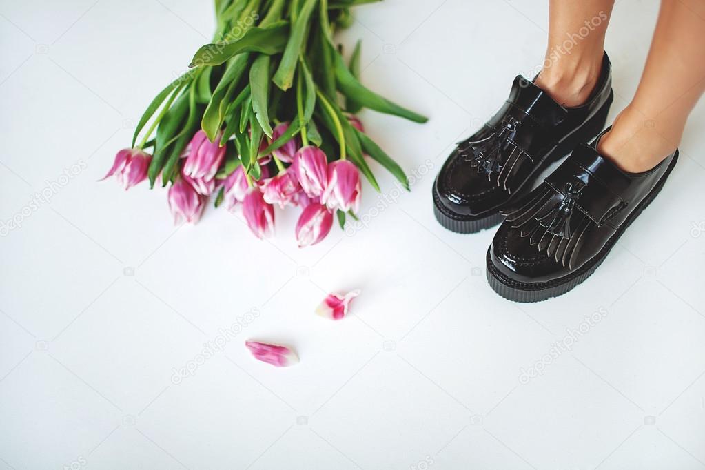 Fine trendy black leather brogues on women legs with flowers