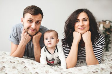 Mutlu genç anne ve bebek çocuk yatakta yatarken baba