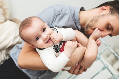 Gülümseyen bebek bacağından öpüşme genç mutlu baba