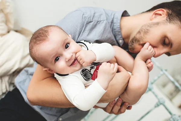 Young happy father kissing smiling baby in leg — Stock Photo, Image