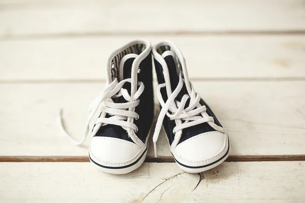Sneakers baby in bianco e nero sul pavimento in legno — Foto Stock