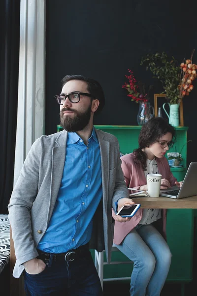 Homme d'affaires en lunettes avec smartphone sur femme travaillant sur bac — Photo