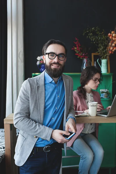 Empresário em óculos com smartphone sobre mulher trabalhando no bac — Fotografia de Stock