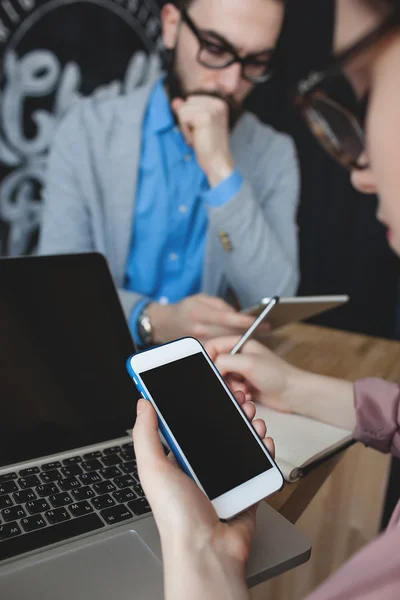 Vrouw met smartphone notities over laptop in café — Stockfoto