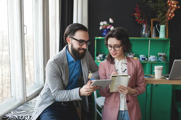 Homme d'affaires et femme collaborant en utilisant une tablette et un bloc-notes — Photo