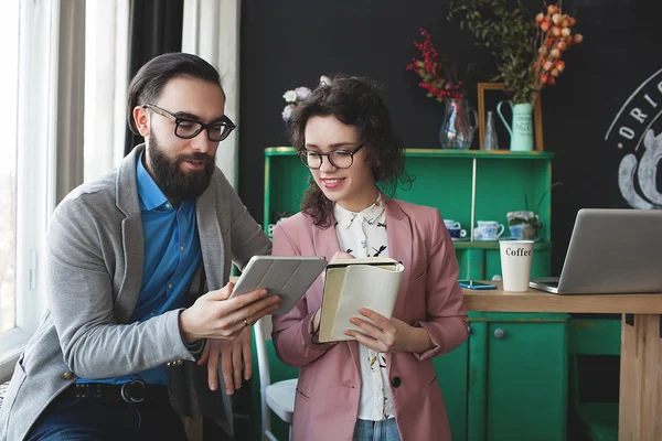 Homme d'affaires et femme collaborant en utilisant une tablette et un bloc-notes — Photo