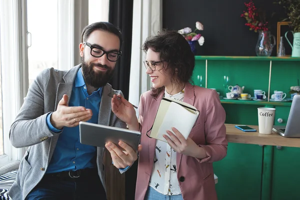 Homme d'affaires et femme collaborant en utilisant une tablette et un bloc-notes — Photo